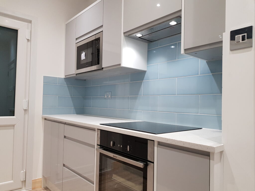 Professional kitchen installation in Mill Hill featuring a built-in oven and a blue metro tiles as the main focal points