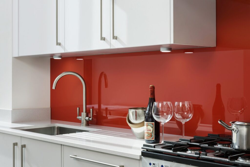 Professional kitchen installation in Hadley Wood featuring a red glass splashback and a quartz worktop as the main focal points.