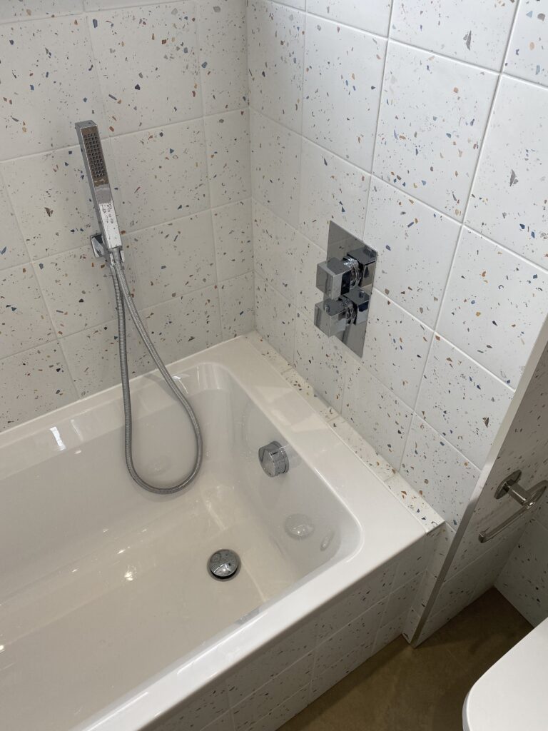 Professional bathroom installation in Arkley featuring a speckle porcelain tiles and a single ended bath as the main focal points