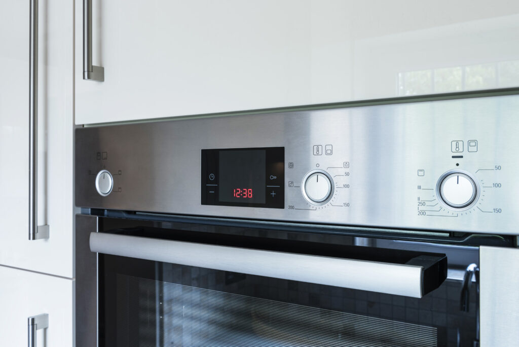 Professional kitchen installation in Arkley featuring a stainless steel oven and a clock display as the main focal points.