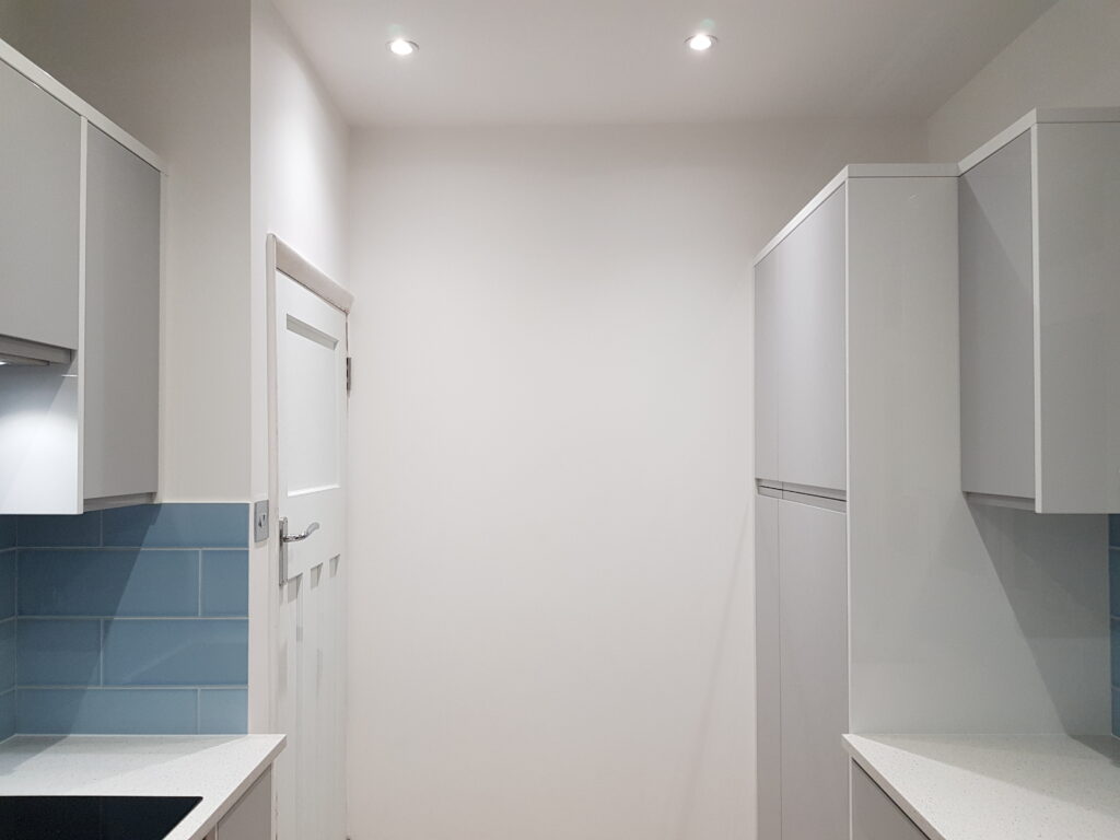 Professional kitchen installation in Mill Hill featuring a tall kitchen units and a blue metro tiles as the main focal points