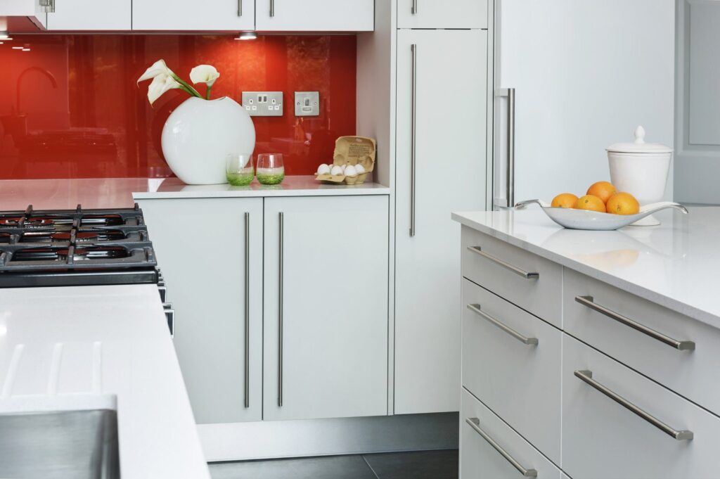 Professional kitchen installation in Hadley Wood featuring a luxury kitchen and a red glass splashback as the main focal points.