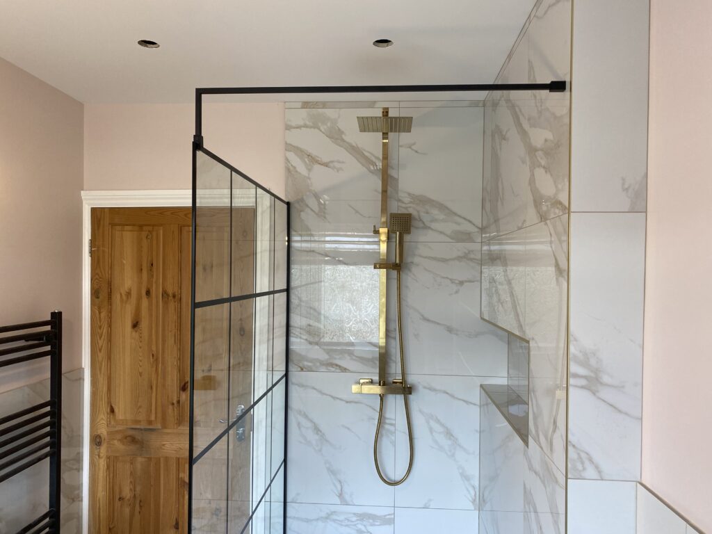 Professional bathroom installation in Hadley Wood featuring a gold exposed shower and a marble tiles as the main focal points