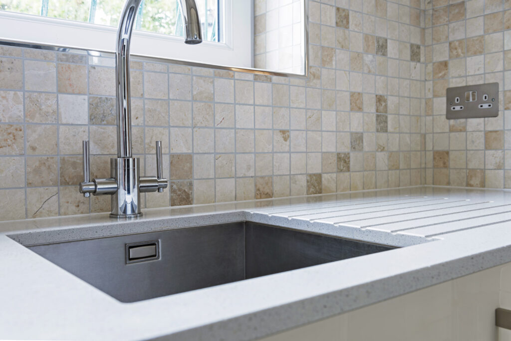 Professional kitchen installation in Arkley featuring a mosaic tiles and a chrome kitchen tap as the main focal points.