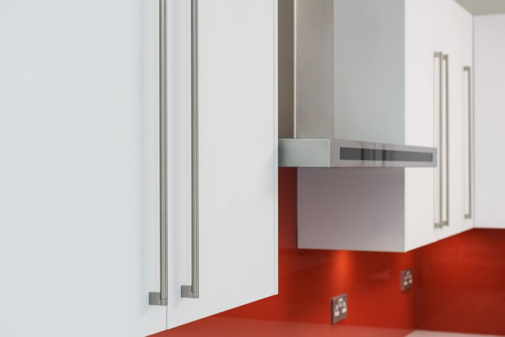 Professional kitchen installation in Hadley Wood featuring a white gloss kitchen and a red glass splashback as the main focal points.