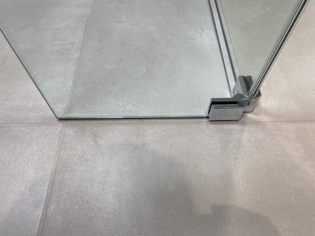 Professional wet room installation in Totteridge featuring a beige tiles and a hinged deflector panel as the main focal points