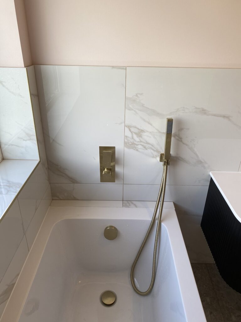 Professional bathroom installation in Hadley Wood featuring a single ended bath and a marble tiles as the main focal points