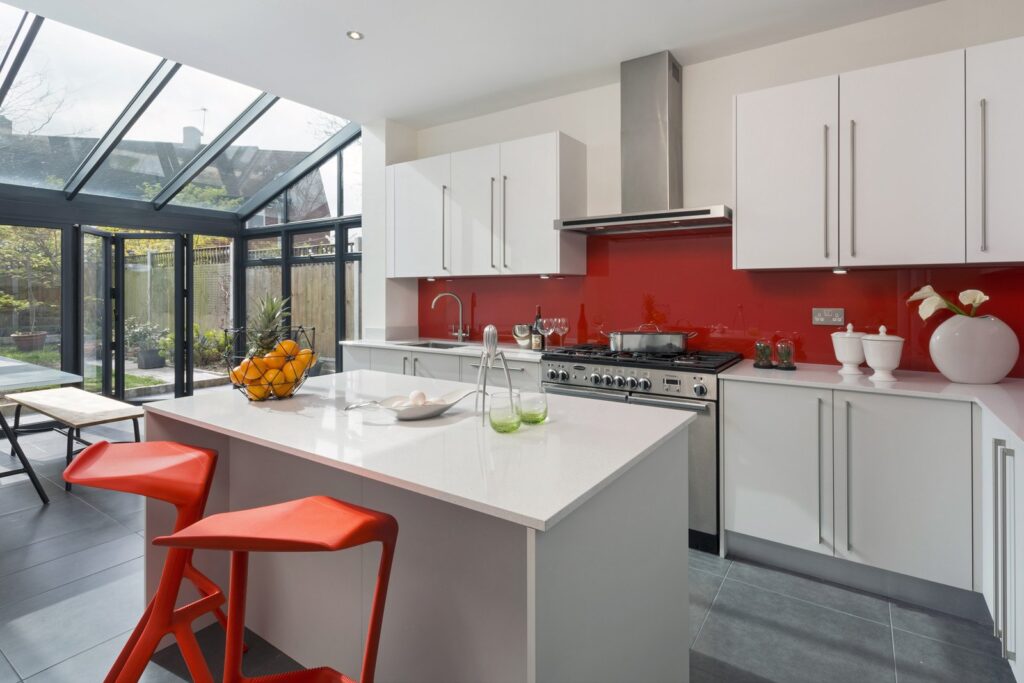 Professional kitchen installation in Hadley Wood featuring a white gloss kitchen and a red splashback as the main focal points