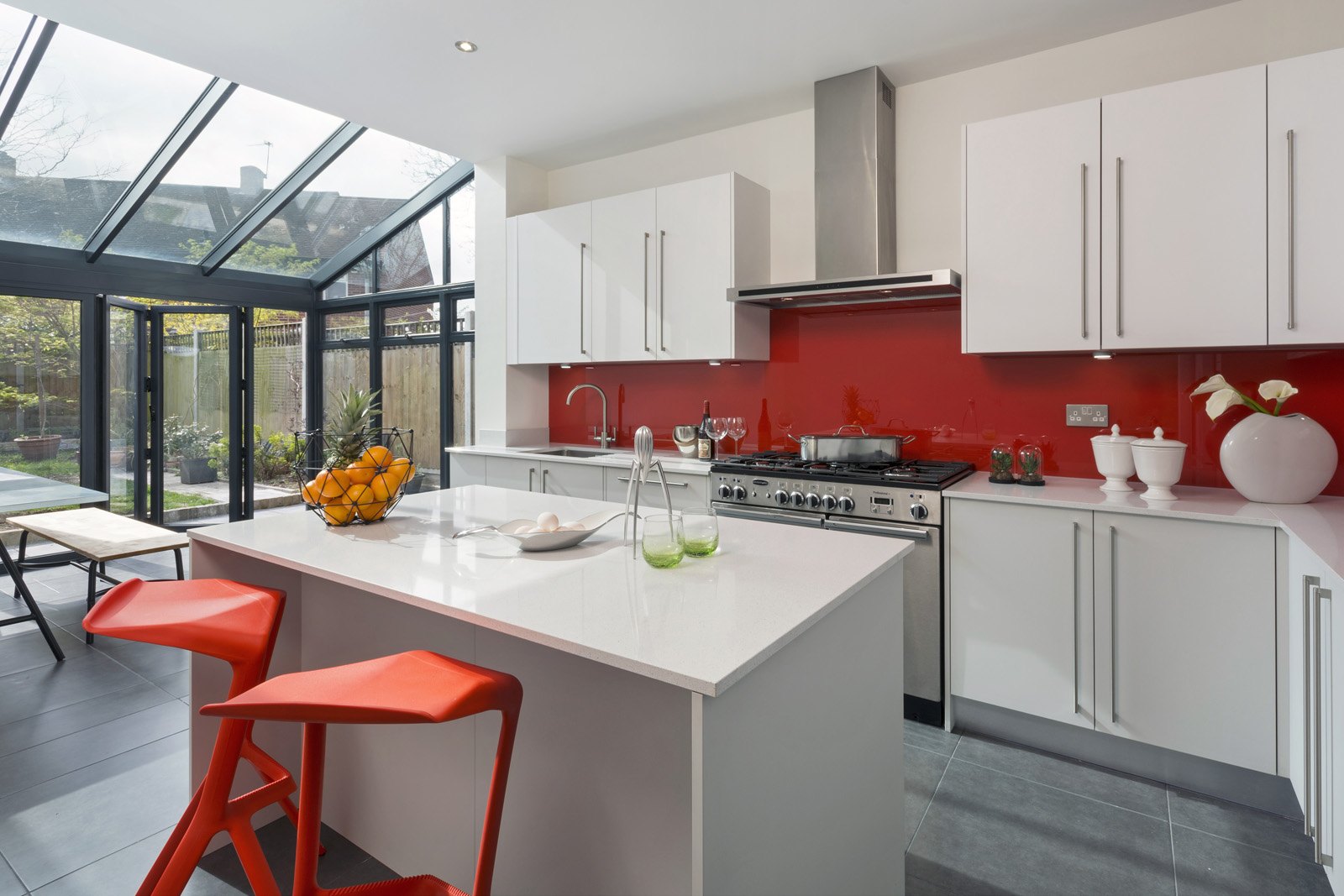 Professional kitchen installation in Hadley Wood featuring a white gloss kitchen and a red splashback as the main focal points