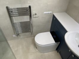 Professional wet room installation in Totteridge featuring a smart toilet and a chrome towel rail as the main focal points. The design is completed with a blue vanity unit and a porcelain tiles for a cohesive modern finish. Project completed by A Martens Kitchens & Bathrooms Ltd. For a free quote, visit https://amartens.co.uk to discuss your wet room renovation. Professional wet room installation in Totteridge featuring a smart toilet and a chrome towel rail as the main focal points