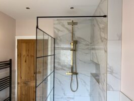 Professional bathroom installation in Hadley Wood featuring a gold exposed shower and a marble tiles as the main focal points. The design is completed with a black shower screen and a shower niche for a cohesive modern finish. Project completed by A Martens Kitchens & Bathrooms Ltd. For a free quote, visit https://amartens.co.uk to discuss your bathroom renovation. Professional bathroom installation in Hadley Wood featuring a gold exposed shower and a marble tiles as the main focal points