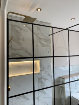 Professional bathroom installation in Hadley Wood featuring a black shower screen and a shower niche as the main focal points. The design is completed with a marble tiles and a gold expose shower for a cohesive modern finish. Project completed by A Martens Kitchens & Bathrooms Ltd. For a free quote, visit https://amartens.co.uk to discuss your bathroom renovation. Professional bathroom installation in Hadley Wood featuring a black shower screen and a shower niche as the main focal points